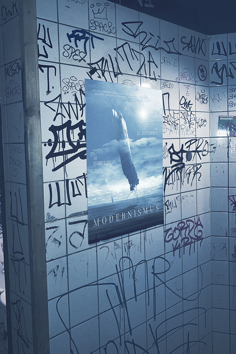 Poster for the Modernismus event hanging in a restroom